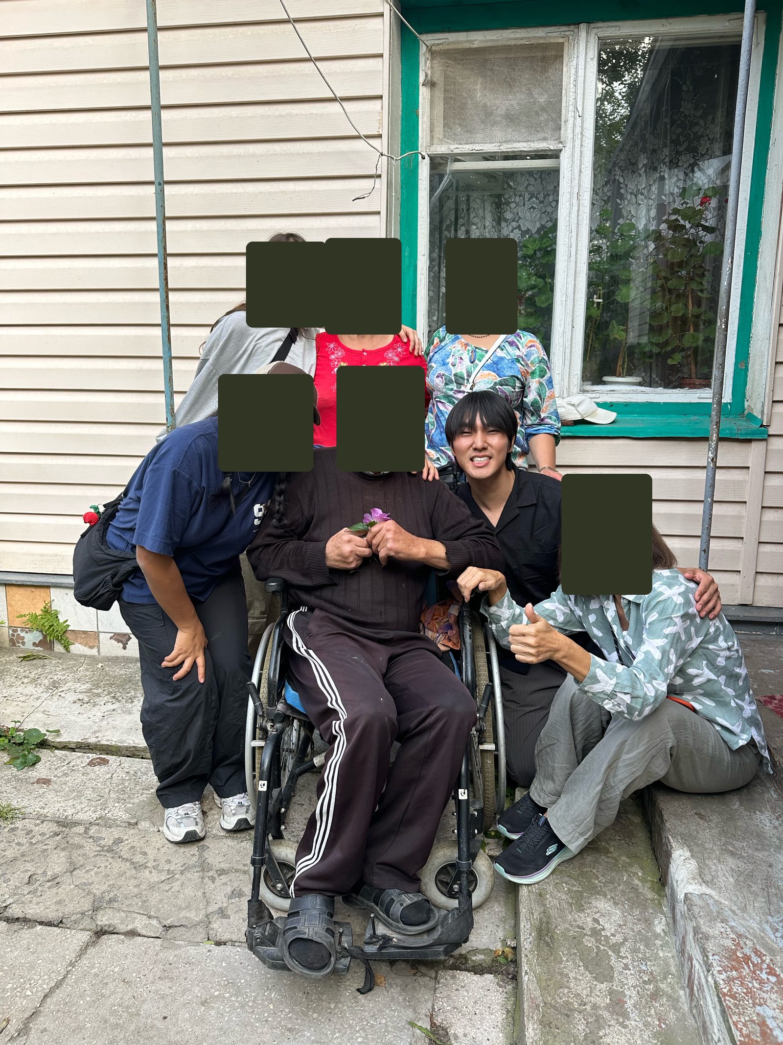 Daniel with a man in a wheelchair and friends; other faces covered